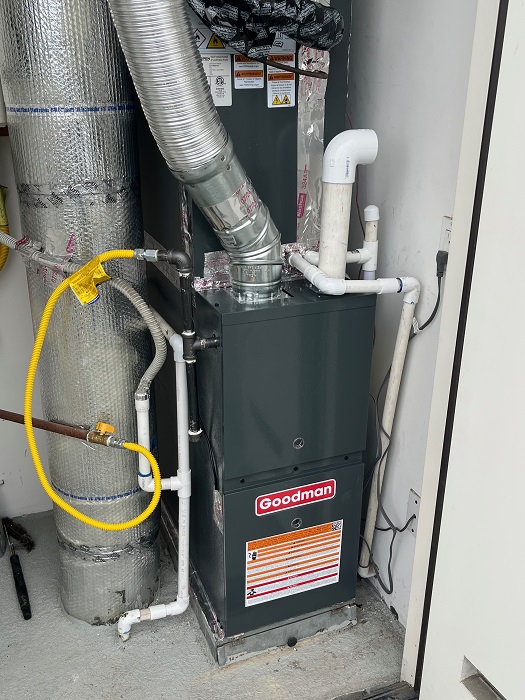 Goodman furnace with metal vent connector, condensate piping, gas piping, and adjacent indoor HVAC equipment